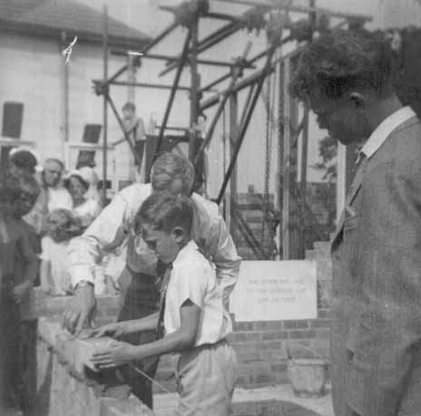 1955. Nigel laying a brick for the new Wimpson Methodist church, while Russon looks on